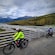 Three people riding bikes on a bridge over a river in Alaska